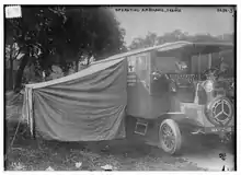 Photographie en noir et blanc d'un camion auquel est appendu une tente en toile.