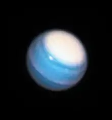 Photographie d'Uranus, des structures nuageuses blanches aux pôles et à l'équateur sont visibles.