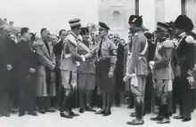 Photographie en noir et blanc représentant Theodor Eicke et des responsables du parti fasciste italien, devant le monument de la victoire de Bolzano.