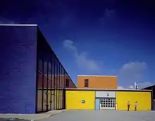 photographie d’un bâtiment aux formes géométriques de couleurs bleu, jaune et orange.