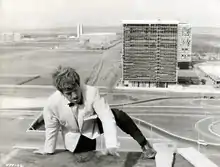 Photographie en noir et blanc d'un acteur se hissant sur le toit d'un immeuble.