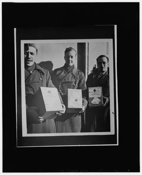 Oflag II-A - Trois officiers belges recevant des colis de la Croix-Rouge américaine - 1942